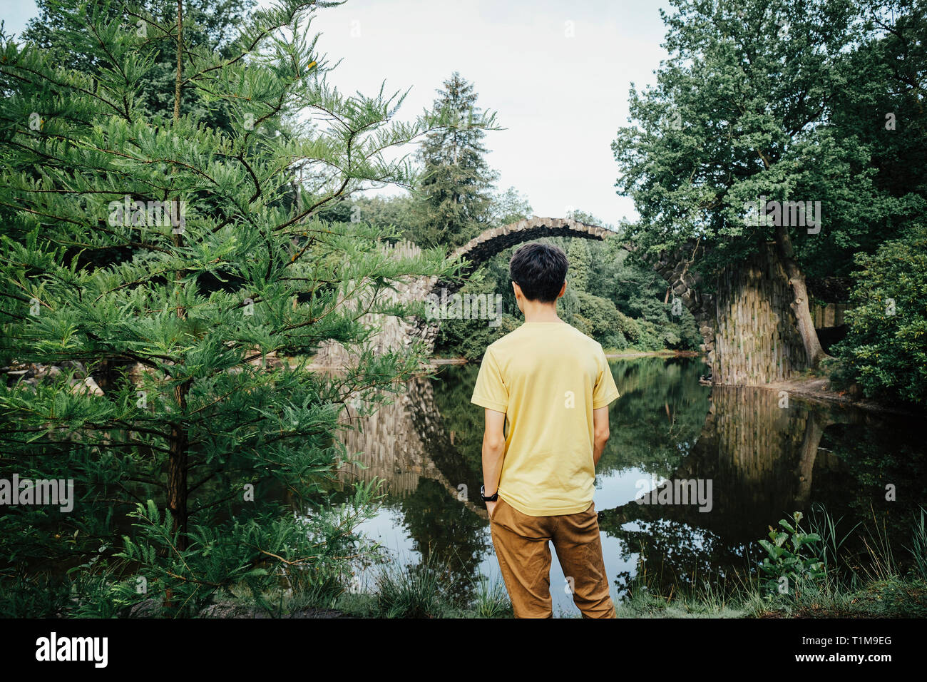 Teenager, der die ruhige Rakotzbrücke Devils Bridge, Rakotzbrücke, Brandenburg, Deutschland, betrachtet Stockfoto