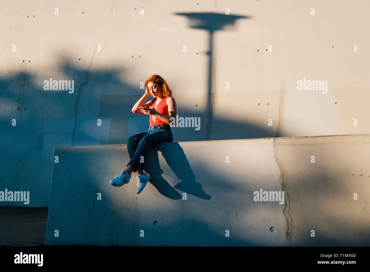 Junge Frau mit Smartphone an der Stadtmauer Stockfoto