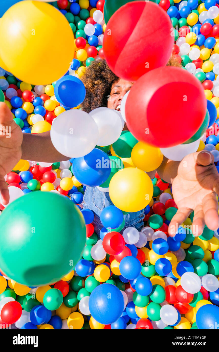 Glücklicher junger Mann, der in einem lebhaften Ballpool spielt Stockfoto