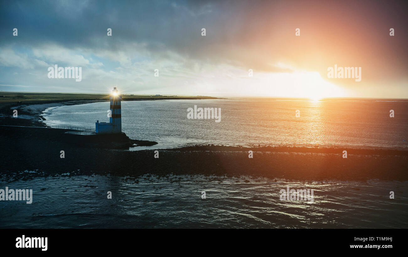 Idyllischen Sonnenuntergang über das Meer und auf den alten Leuchtturm, Reykjanesbær, Island Stockfoto