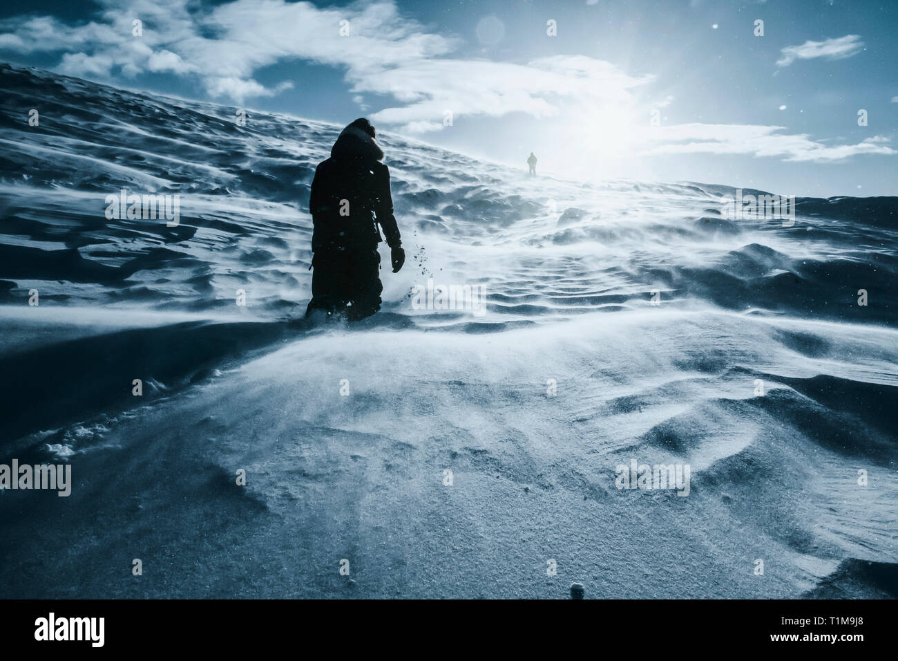 Mann, der durch die sonnige, schneebedeckte Landschaft läuft, Reykjadalur, Island Stockfoto