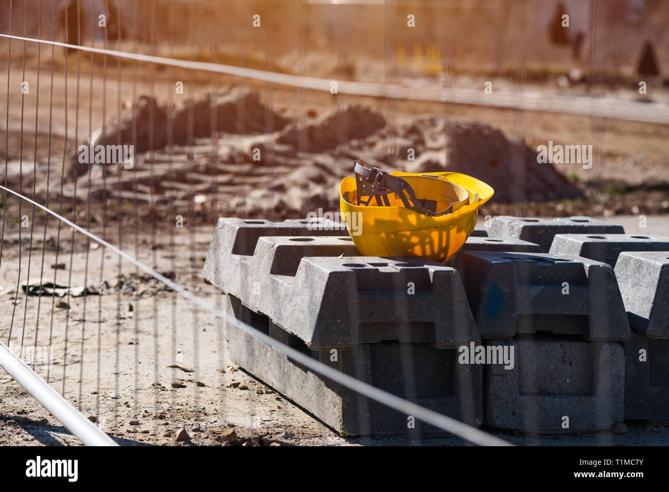 Gelbe Schutzhelm auf Baustelle in Mittag beim Start Pause. Nicht erkennbare defokussierten Bauarbeiter im Hintergrund sichtbar. Stockfoto