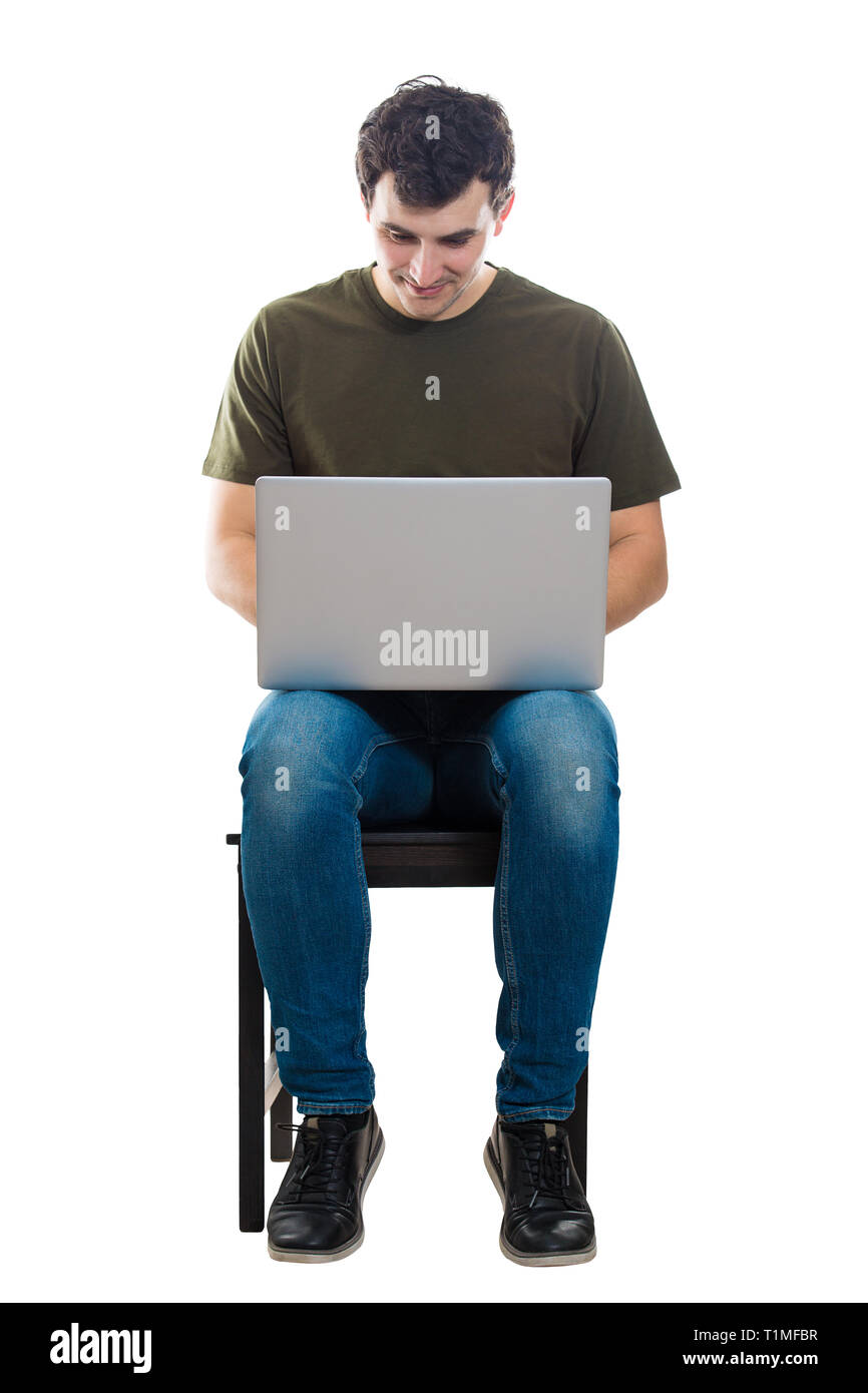 Fröhlicher junger Mann bei der Arbeit auf dem Laptop, auf einem Stuhl auf weißem Hintergrund sitzt. Kreative Freiberufler Kerl, die von zu Hause aus arbeiten an seinem Notebook compu Stockfoto