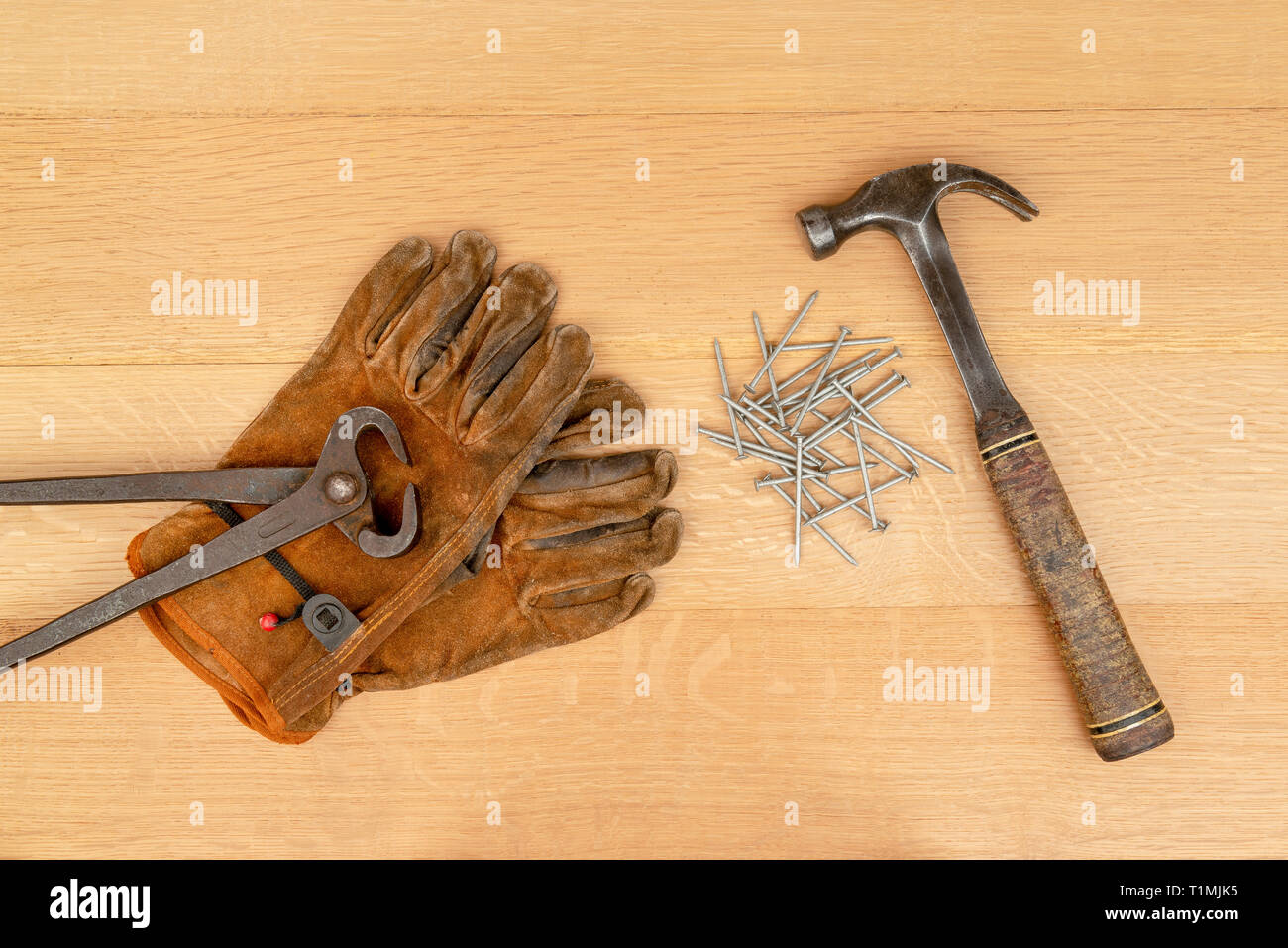 Jahrgang Paar lange Griff Seitenschneider Zangen und gut getragen Leder Arbeitshandschuhe alten Hammer und Nägel Holz Hintergrund Stockfoto
