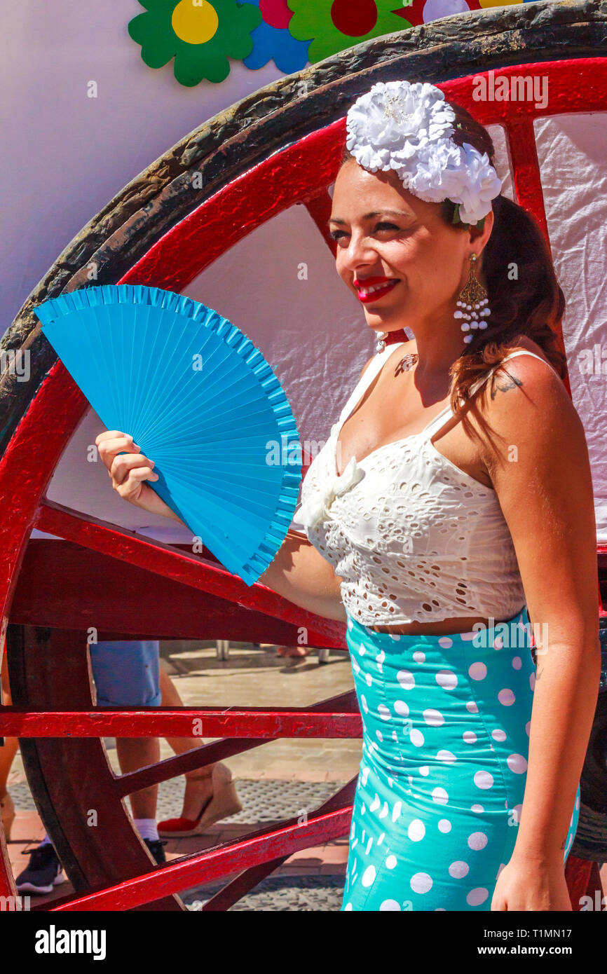 Arroyo de la Miel, Spanien - 17. Juni 2018: Mädchen mit Ventilator das Tragen eines fascinator an einem lokalen Fiesta. Spanien ist bekannt für seine Feste. Stockfoto