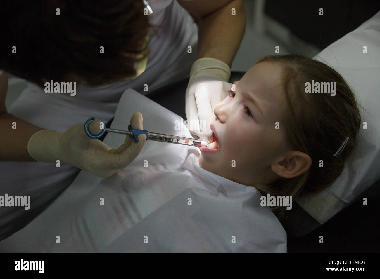 Kleines Mädchen am Zahnarzt, lokale Anästhesie Injektion in das Zahnfleisch, Zahnarzt numbing Gummis für zahnmedizinische Arbeit. Kinder Zahnpflege Konzept. Stockfoto