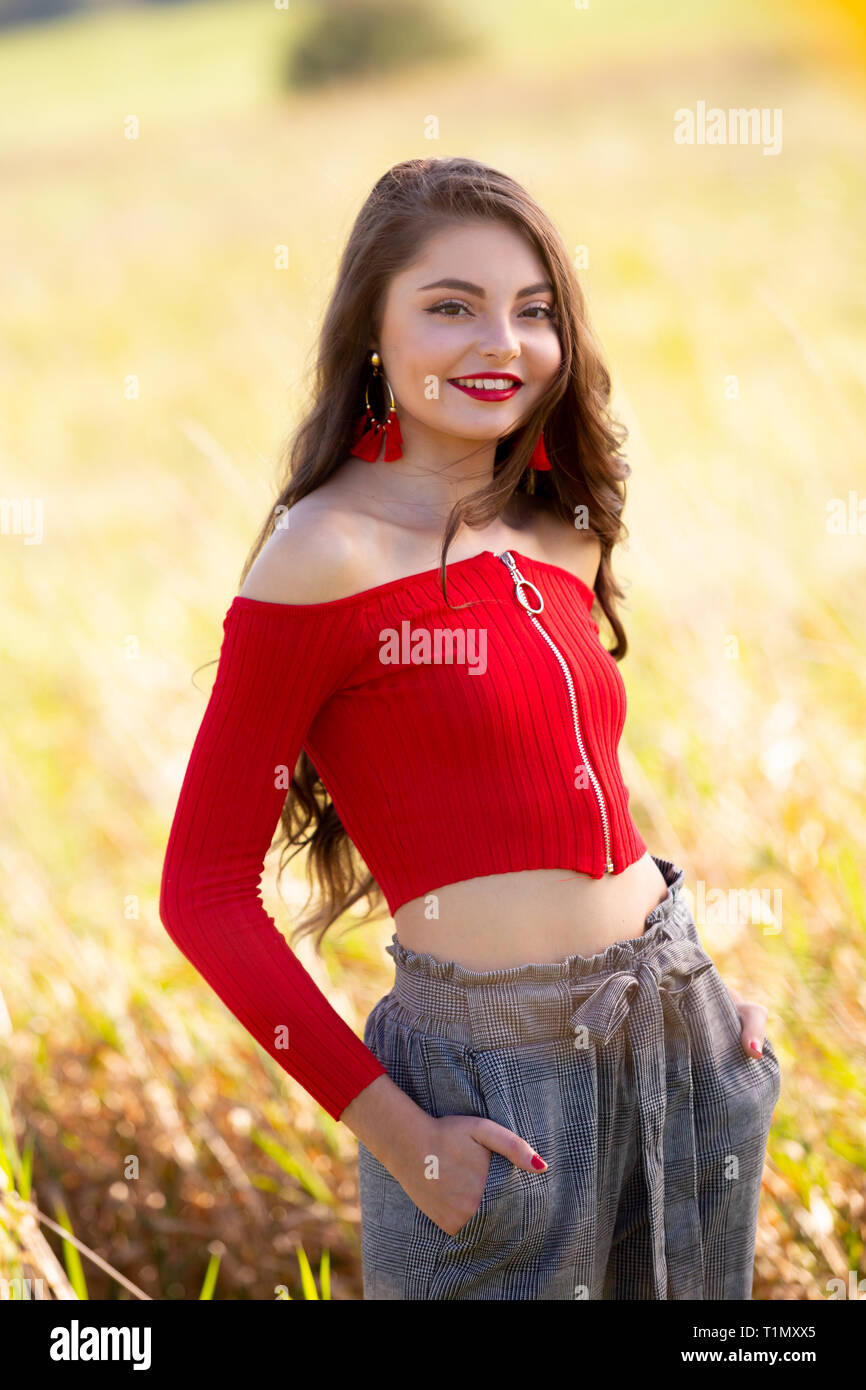 Eine schöne weibliche caucasain High School Girl in Red Top Pullover zu Fuß außerhalb in einem Bauernhof Feld Sommer. Stockfoto