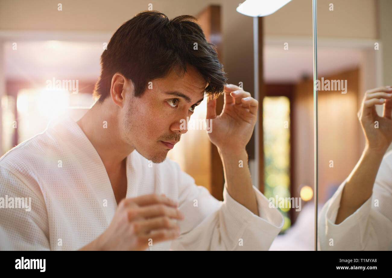 Mann Haare im Badezimmer Spiegel prüfen Stockfoto