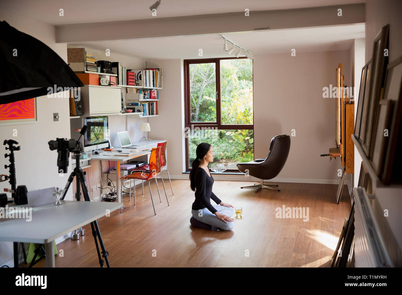 Junge Frau meditieren auf dem Boden im Home Office Stockfoto