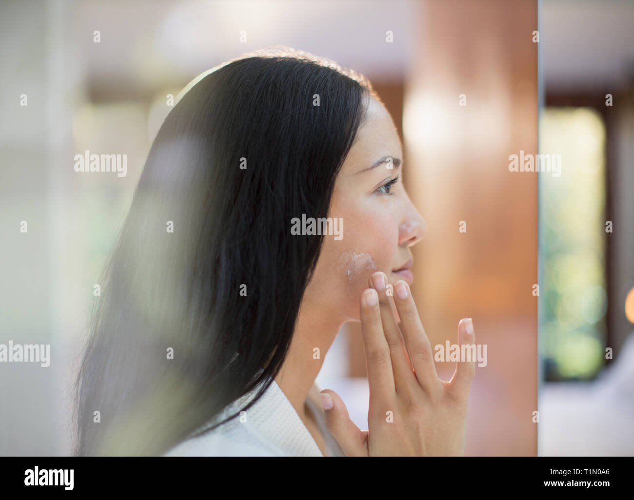 Profil junge Frau Anwendung Feuchtigkeitscreme Wange Stockfoto