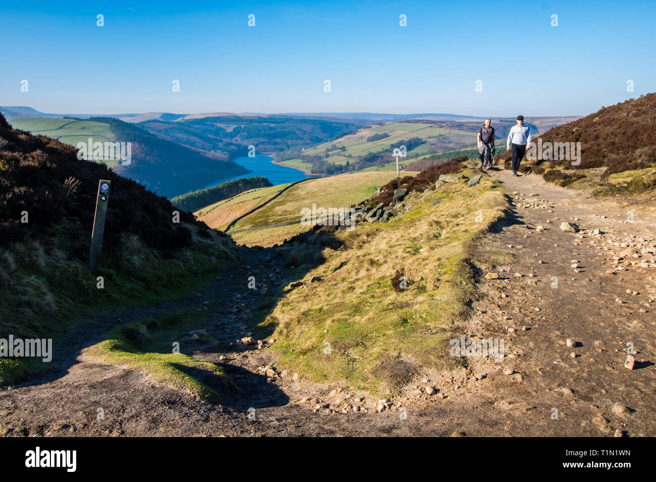 Zwei Wanderer auf dem Fußweg in der Nähe von Whinstone Lee Tor, Derwent Kante, Englisch Peak District, mit Ladybower Reservoir in der Ferne Stockfoto