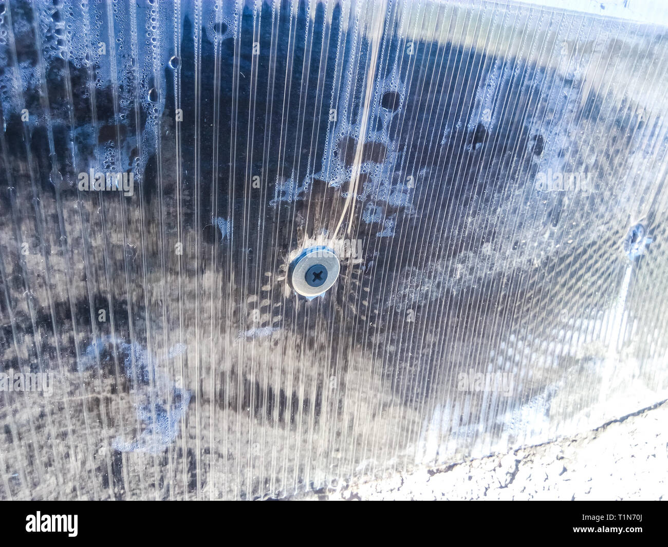 Verbindungselemente aus Polycarbonat mit einer Schraube an einen Holzbalken. Installation, Gewächshaus Gewächshaus für Gemüse. Polycarbonat Gewächshaus aus Gleichheit montiert Stockfoto