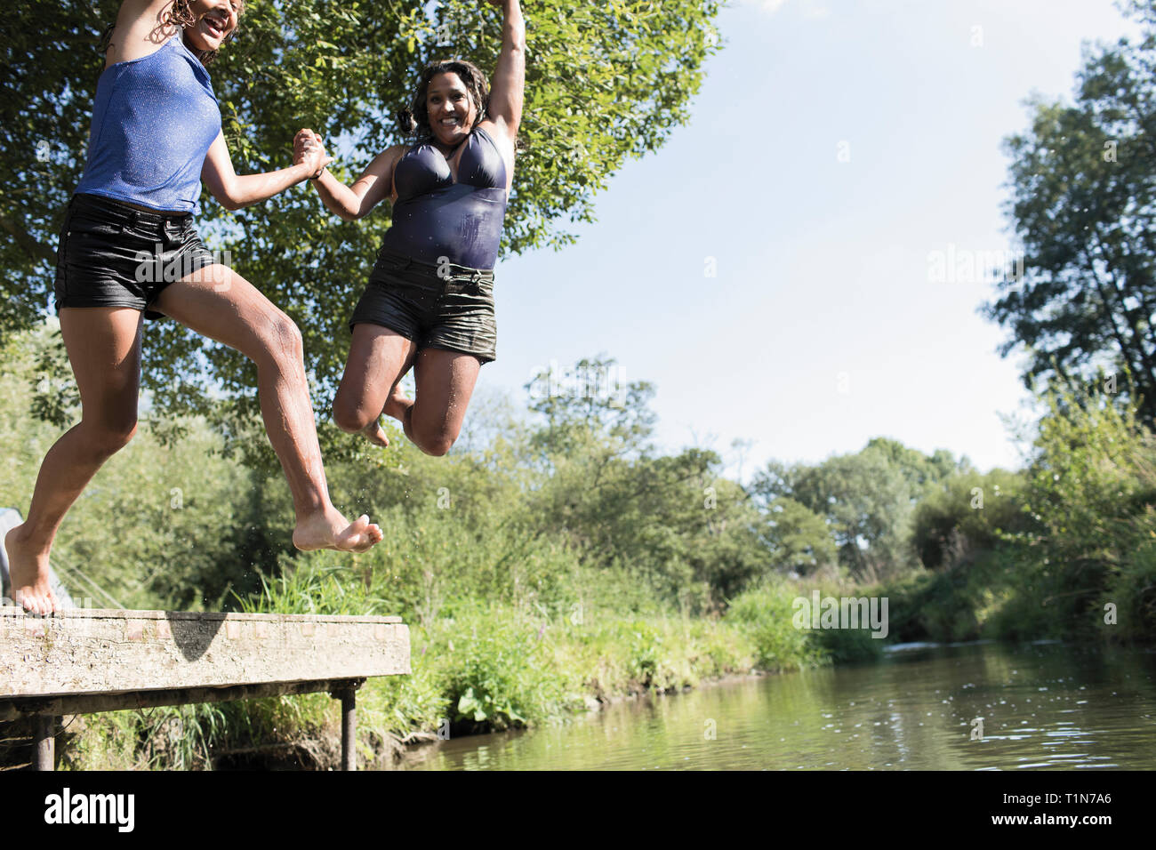 Verspielte Mutter und Tochter in sonnigen Fluss springen Stockfoto