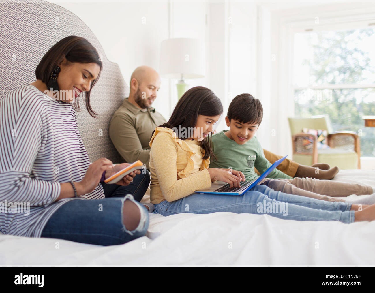 Familie mit Technologie auf dem Bett Stockfoto