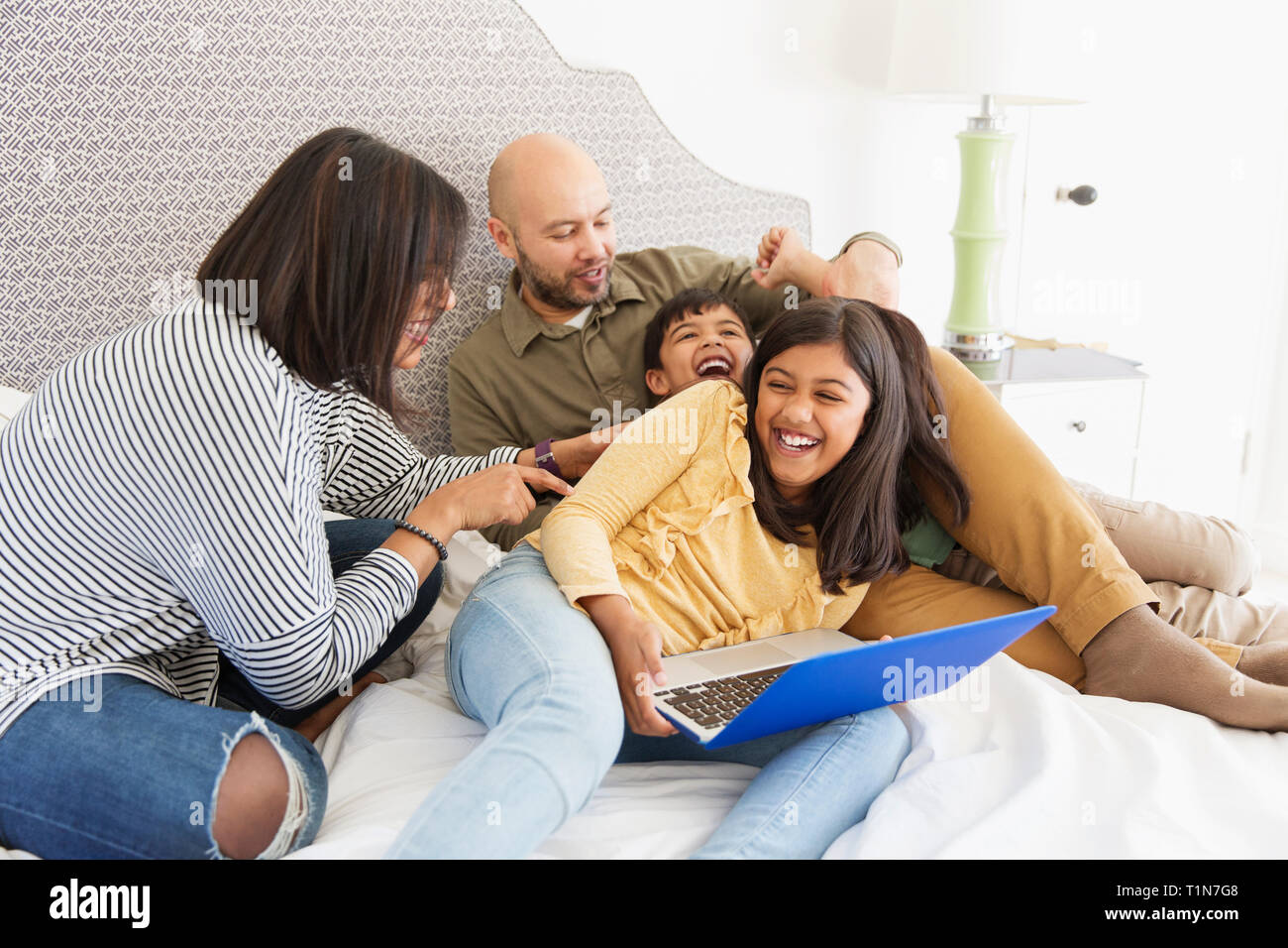 Verspielte Familie mit Laptop auf dem Bett Stockfoto