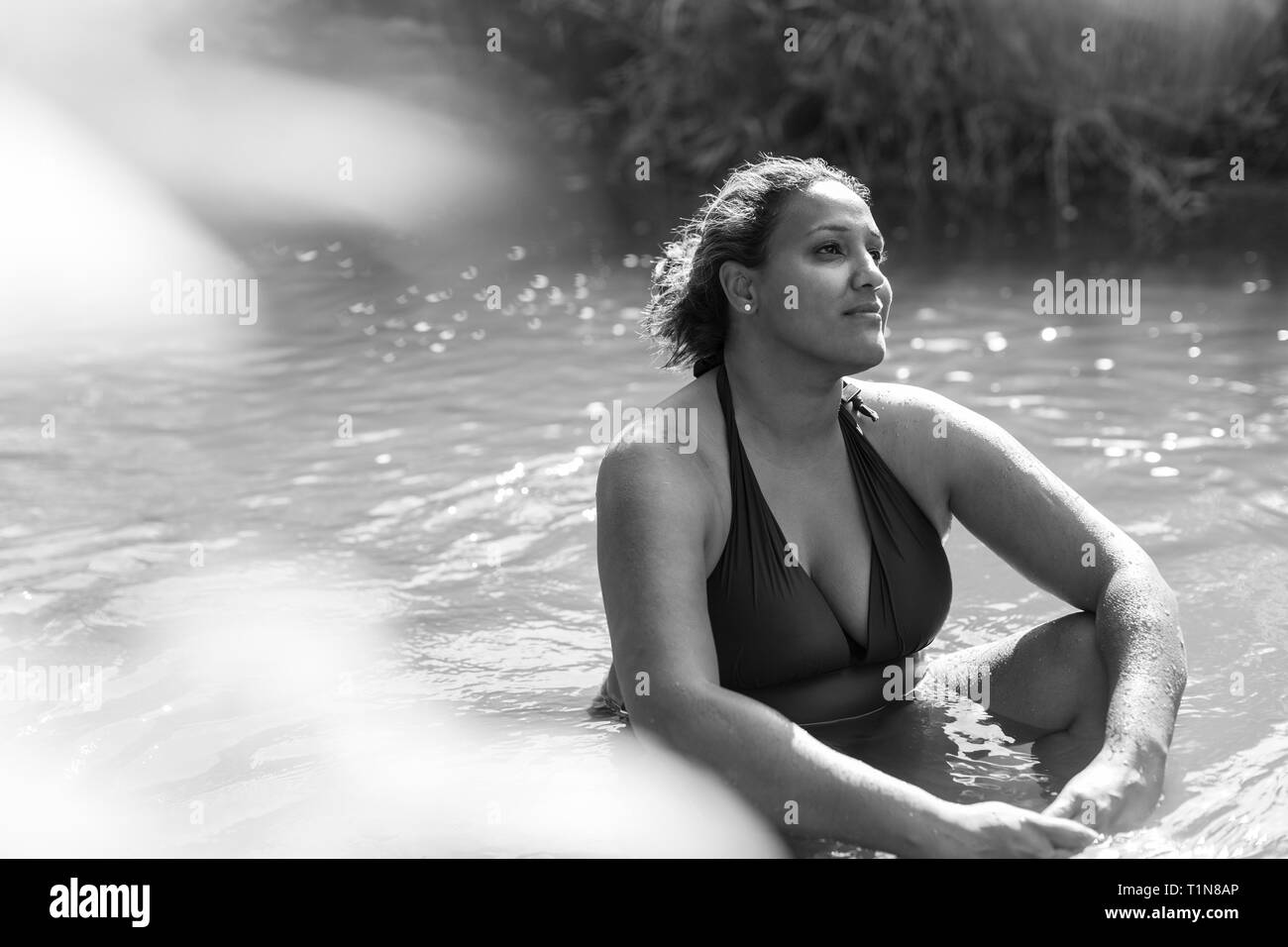 Heitere Frau im sonnigen Fluss sitzen Stockfoto