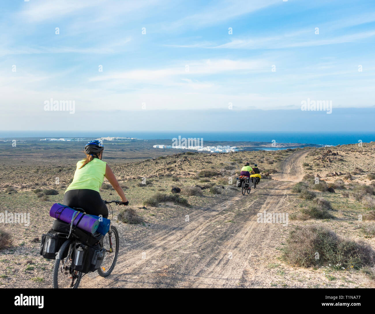 Drei Frauen auf Radtour von Lanzarote, Kanarische Inseln, Spanien. La Santa in der Entfernung. Stockfoto