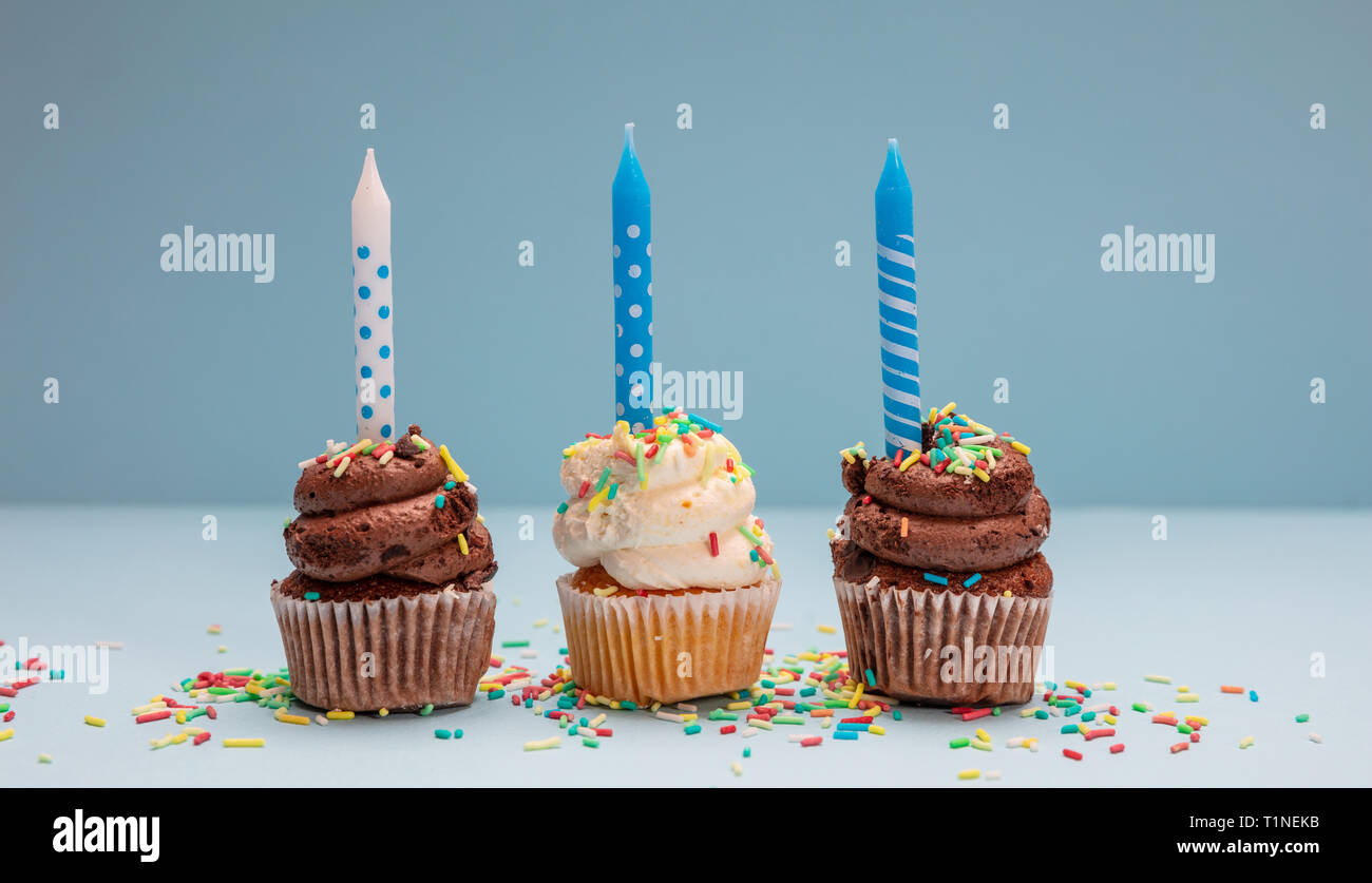 Geburtstag Cupcakes auf Blau pastell Hintergrund. Drei cupcakes Vanille und Schokolade mit blauen Kerzen Stockfoto