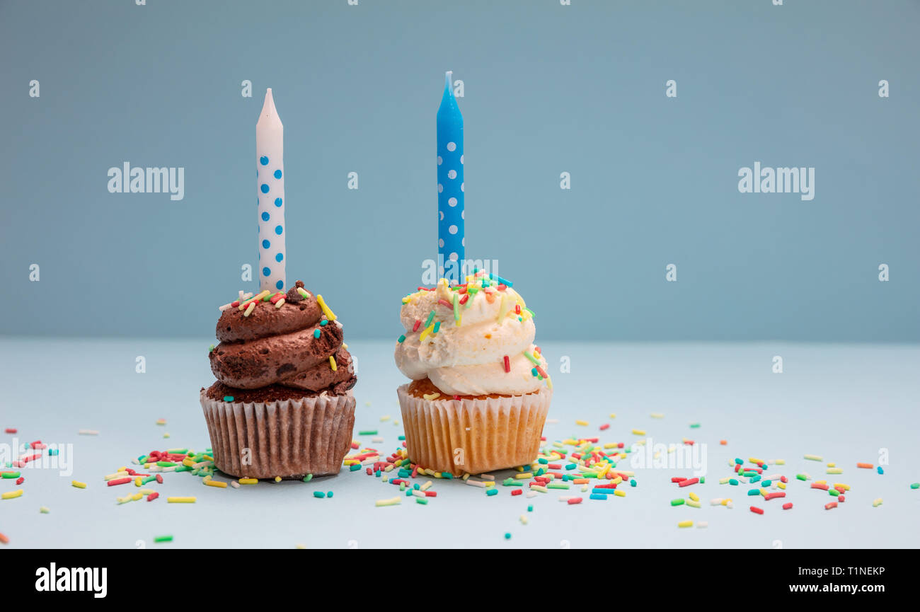 Geburtstag Cupcakes auf Blau pastell Hintergrund. Zwei cupcakes Vanille und Schokolade mit blauen Kerzen, kopieren. Stockfoto