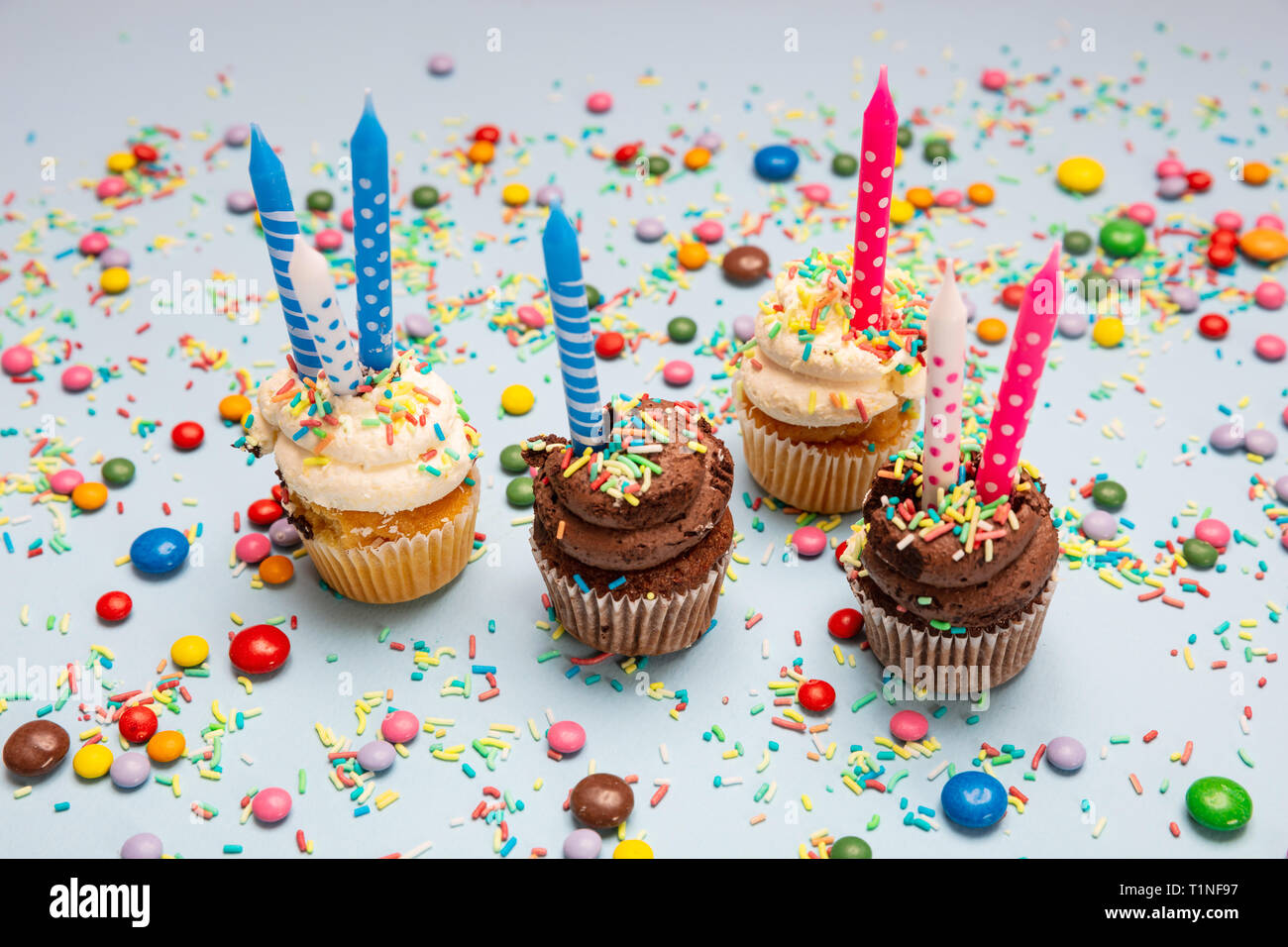 Geburtstag Cupcakes auf Blau pastell Hintergrund. Vier cupcakes Vanille und Schokolade mit Blau und Rosa Kerzen Stockfoto