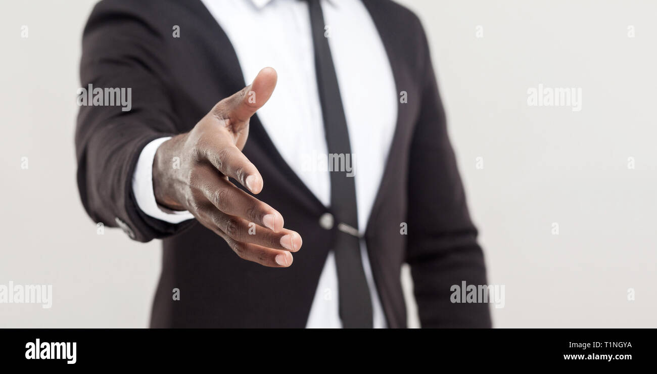 Hand in schwarzem Anzug und Krawatte Hand zur Begrüßung oder Handshake an Kamera. Fokus auf Hand. indoor Studio shot, auf hellgrauem Hintergrund co isoliert Stockfoto