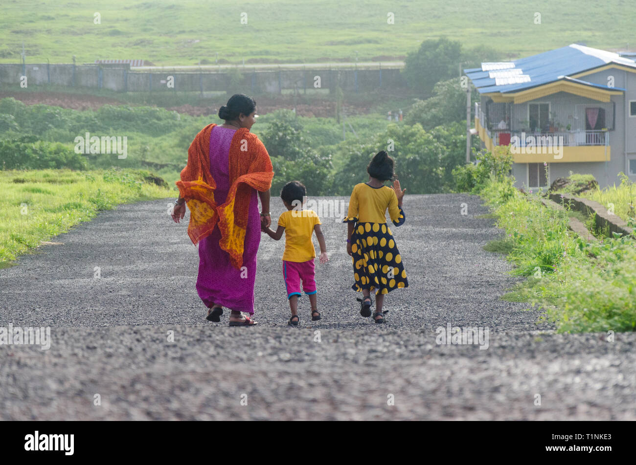 Ansicht von der Rückseite einer indischen Mutter mit ihren zwei Töchtern nach Hause nach einem abendlichen Spaziergang ein. Stockfoto