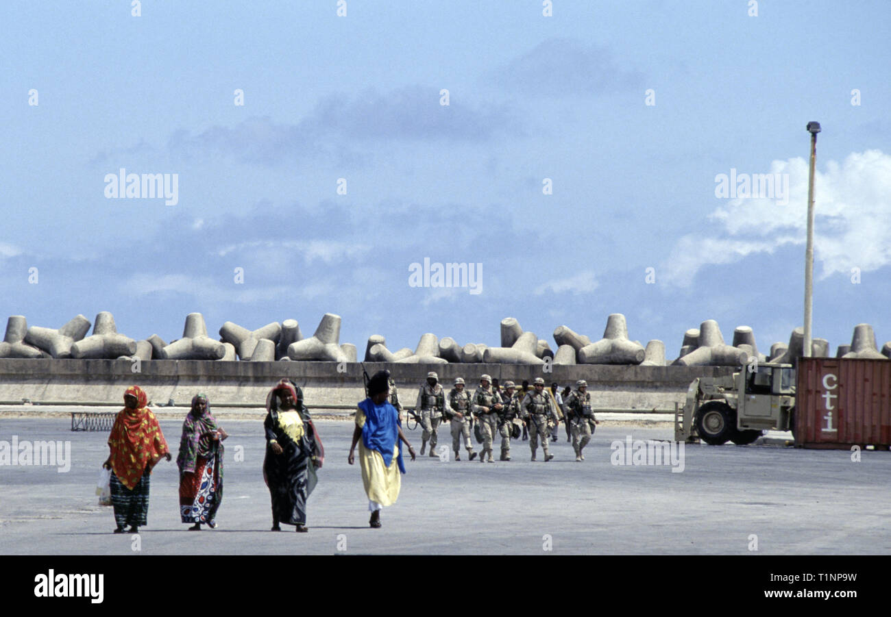 29th. Oktober 1993 hinter vier somalischen Frauen im neuen Hafen in Mogadischu, Somalia, steht eine Gruppe von neuangekommenen Soldaten der US-Armee der Infanterie-Division 24th, des Bataillons 1st des Panzerregiments 64th. Stockfoto