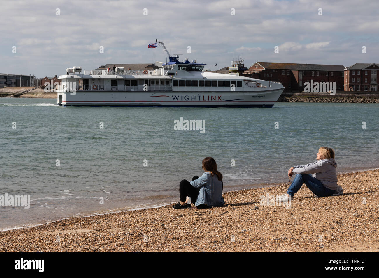 Mutter und Tochter in der Sonne am Strand von Portsmouth Pebble Beach Stockfoto