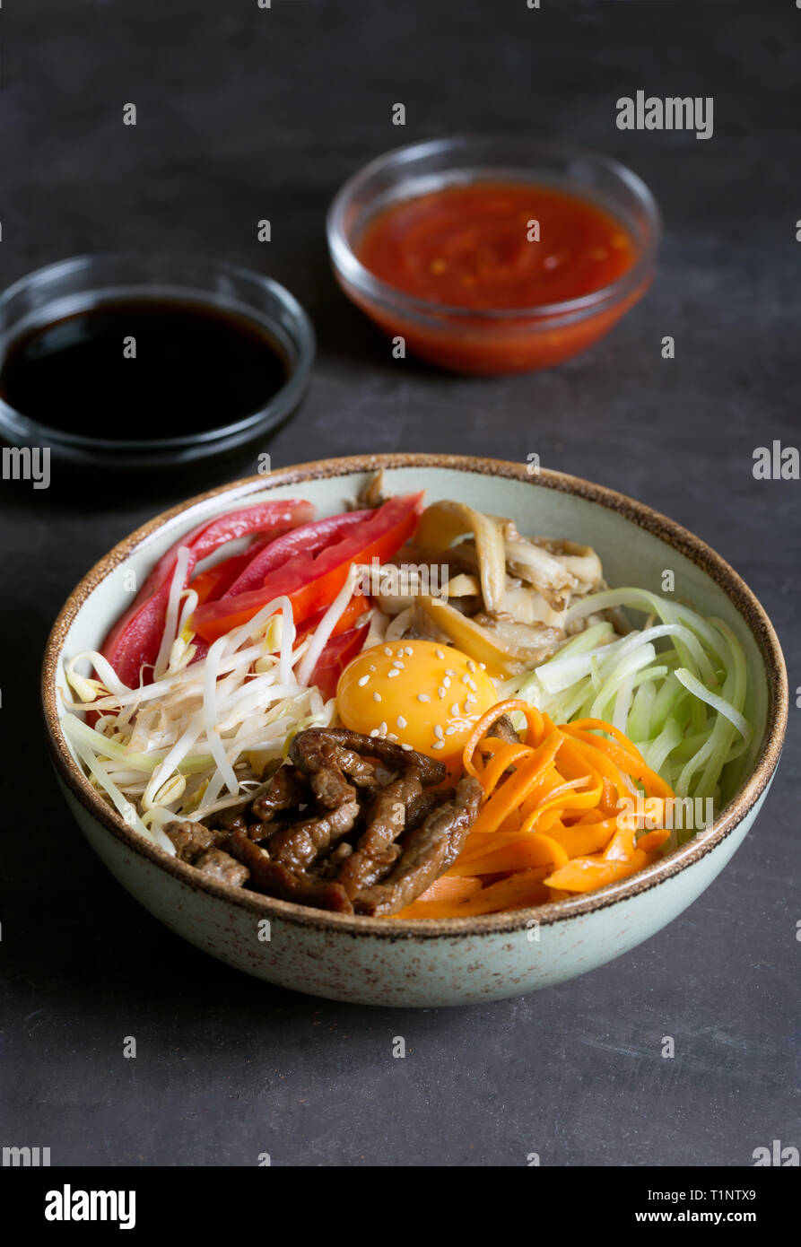 Koreanische Reisgericht Bibimbap. In der Regel als eine Schüssel mit warmem weißer Reis mit Gemüse und Ei serviert. Schwarzer Hintergrund Stockfoto Koreanische Reisgericht Bibimbap. In der Regel als eine Schüssel mit warmem weißer Reis mit Gemüse und Ei serviert. Schwarzer Hintergrund Stockfoto