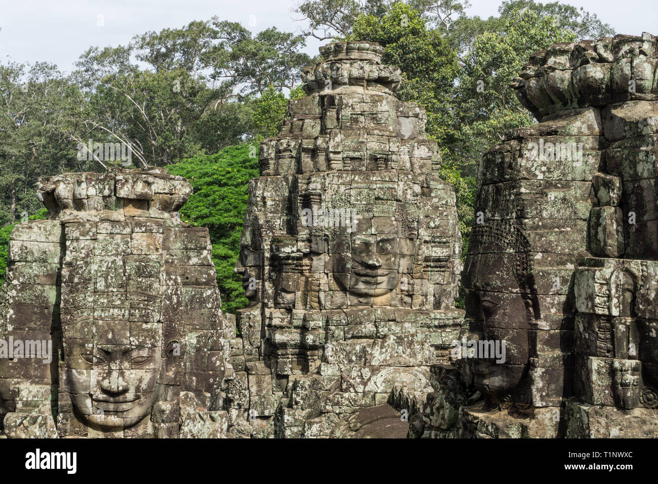 Schönes Bild von drei Stein Gesichter am Bayon Tempel in der Nähe von Angkor Wat mit üppigen Dschungel Vegetation im Hintergrund Stockfoto
