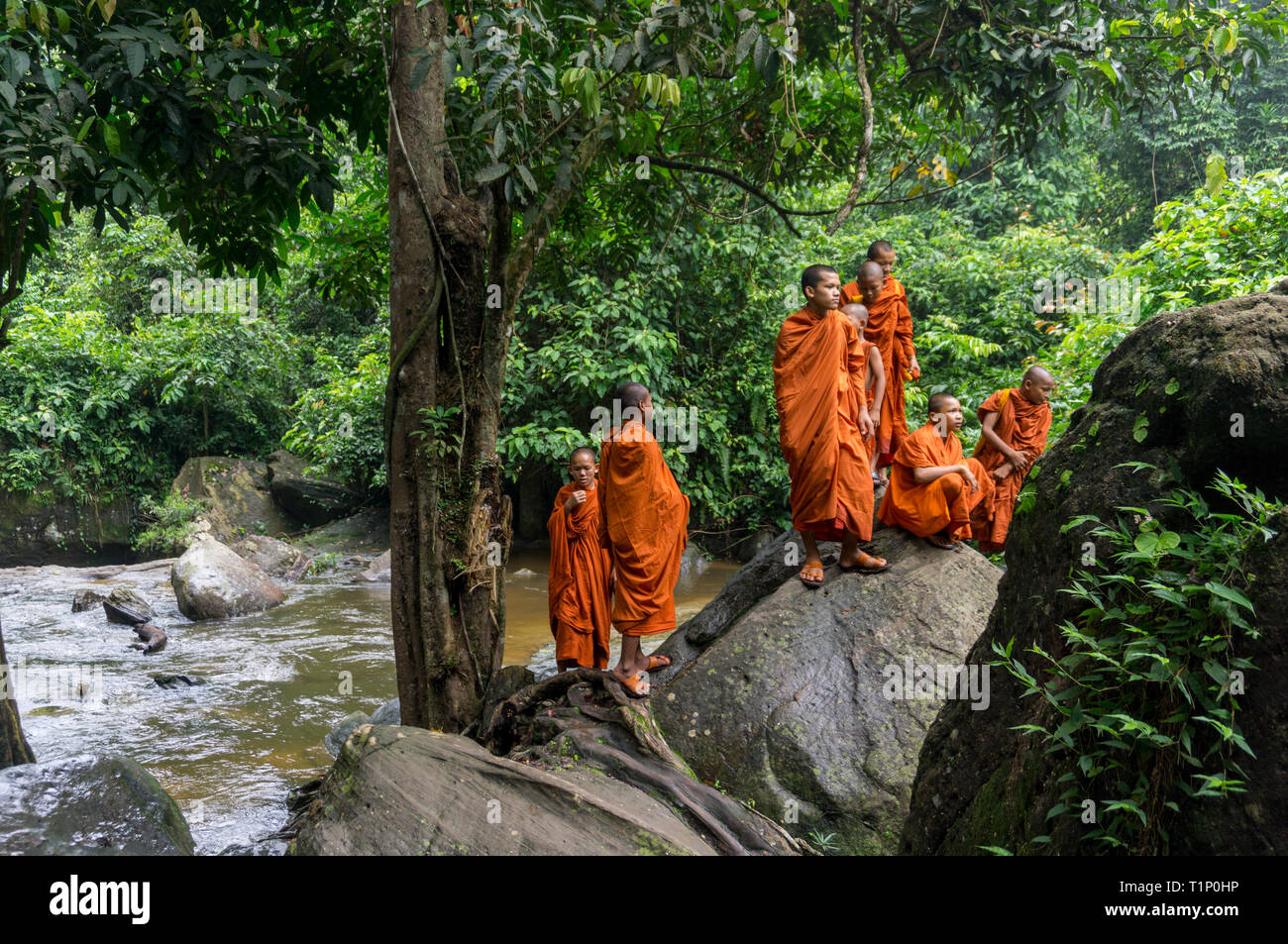 Kulen Mountain, Siem Reap, Kambodscha - 24. Juli 2018: Eine Gruppe junger buddhistischer Mönche ruhen auf einem großen bounder in der Nähe des Flusses Stockfoto