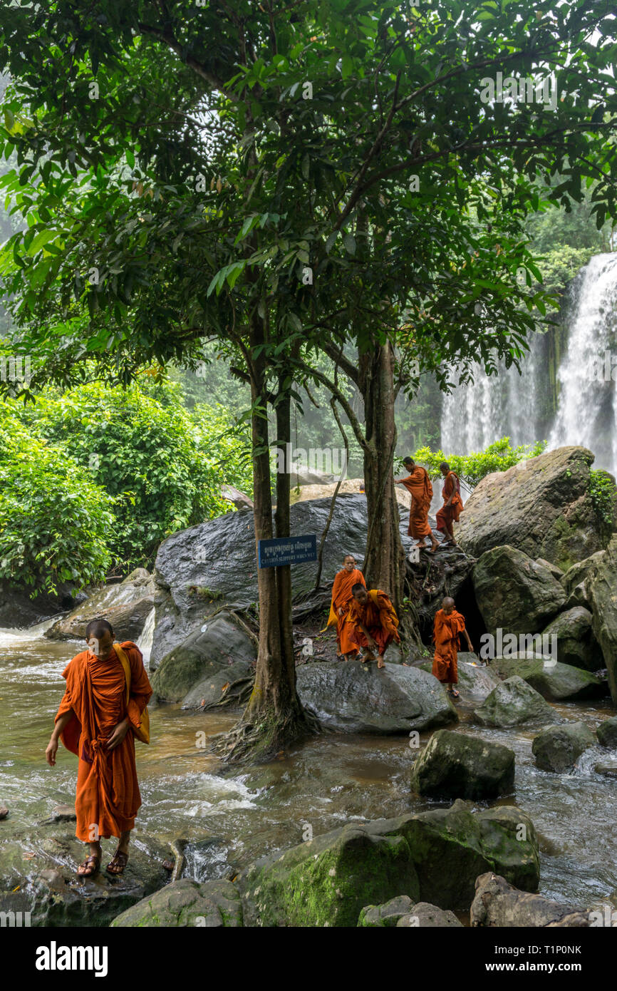 Kulen Mountain, Siem Reap, Kambodscha - 24. Juli 2018: Gruppe von buddhistischen Mönchen Überquerung des Flusses mit einem wunderschönen Wasserfall im Hintergrund Stockfoto