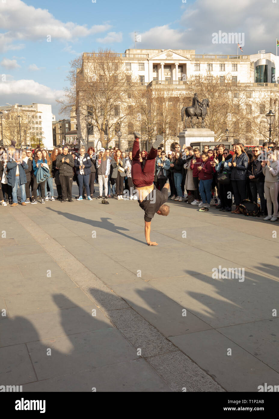 Große Menschenmenge genießt das street Entertainment Show von akrobaten auf dem Trafalgar Square, London, England, UK an einem sonnigen Nachmittag im März. Stockfoto