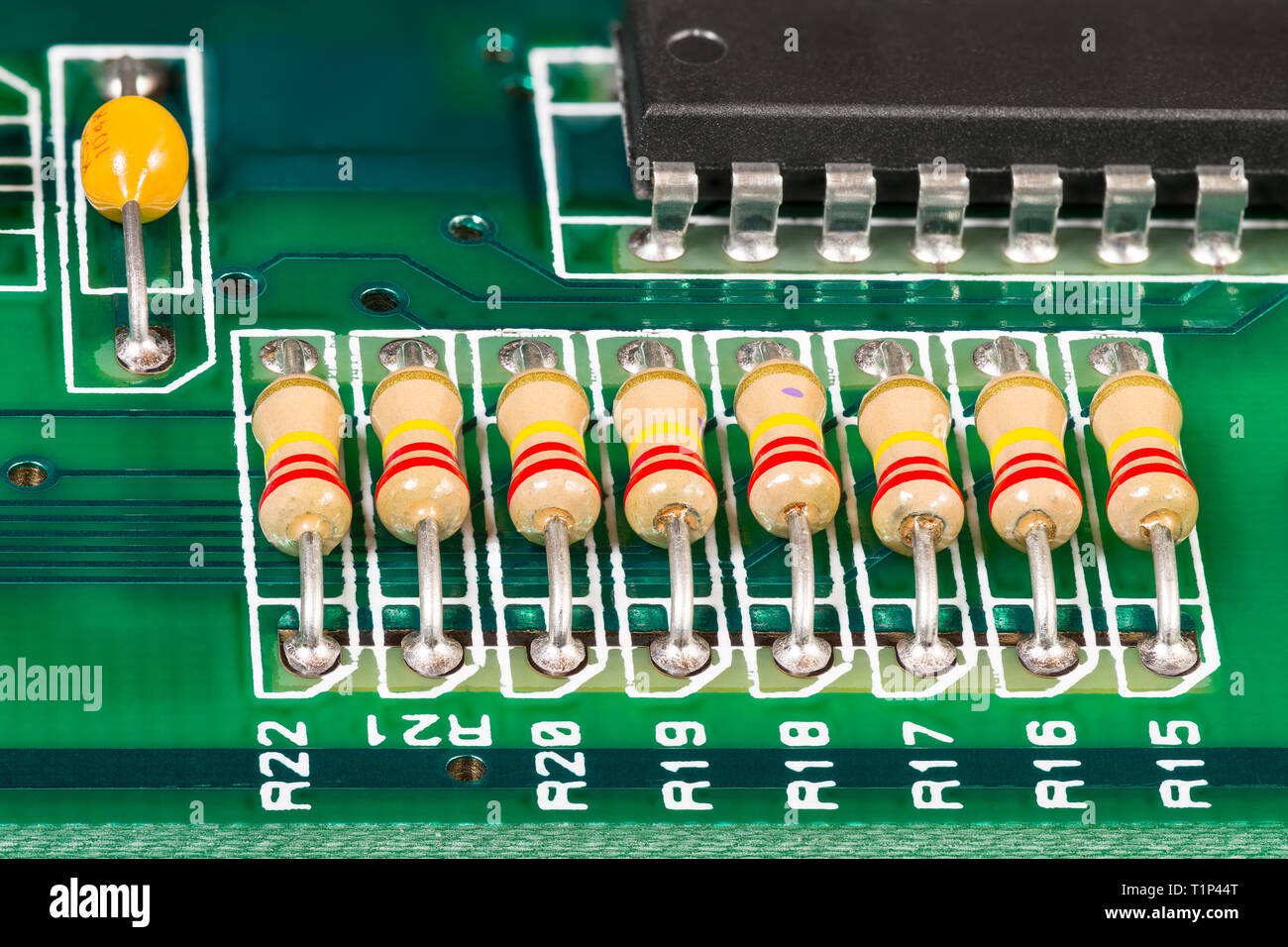 Integrierte Schaltkreise, Widerstände und Kondensatoren aufgelötet auf der FBG. Elektronische Komponenten mit standard Farbe Code und schwarzen Chip. Grün Kupfer board Detail. Stockfoto