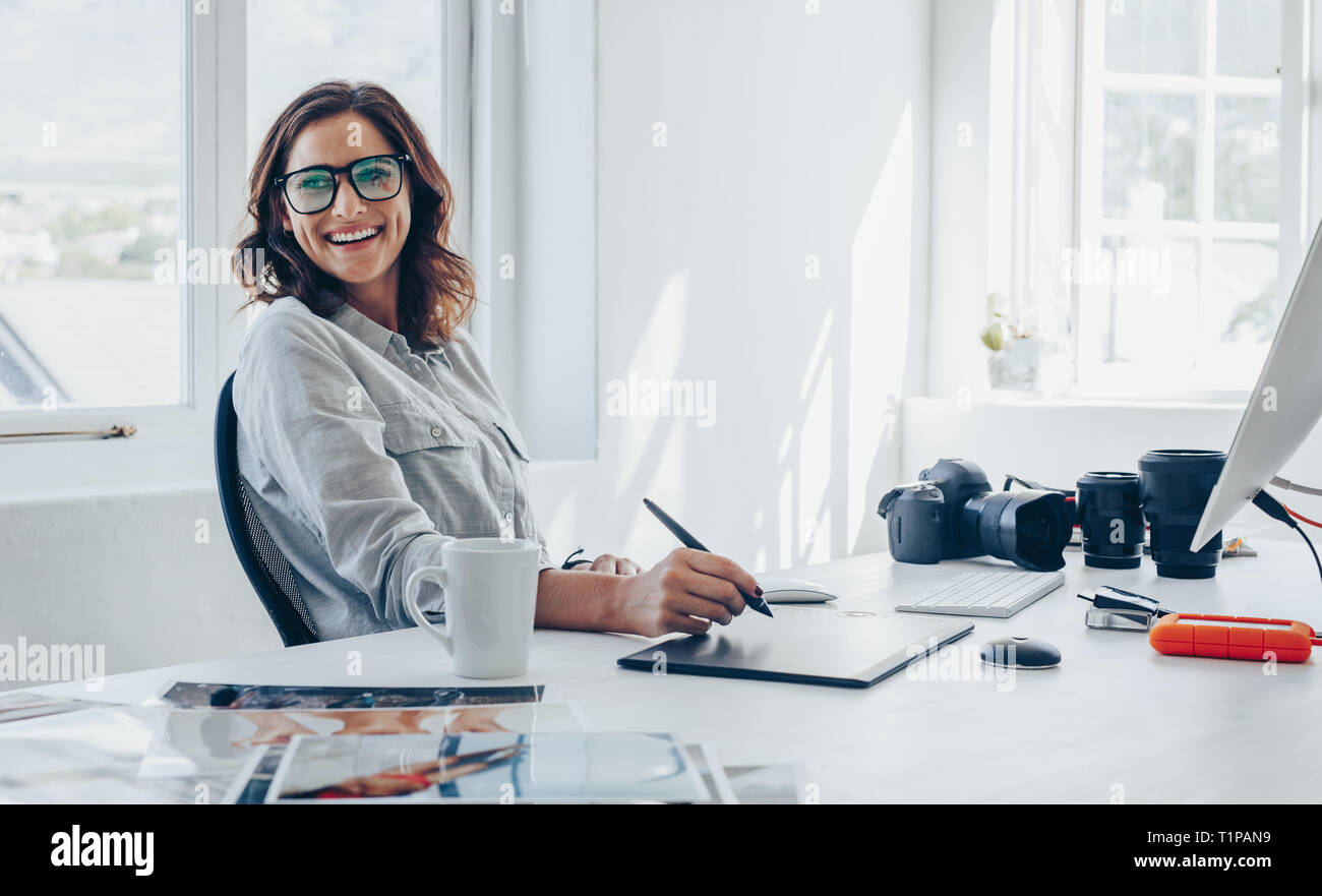 Professionelle Fotografen in ihrem Büro Schreibtisch sitzen und Lächeln. Frau im Büro mit Digital Graphic Tablet- und Zeichenstift. Stockfoto