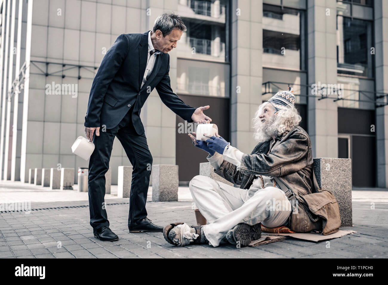 Art aufrichtige kurzhaarige Geschäftsmann sharing Box mit Nahrungsmitteln Stockfoto