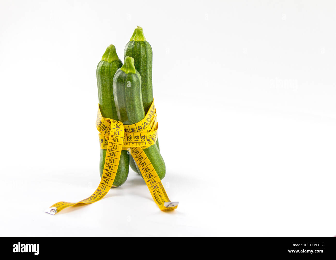 Vegetarische Ernährung, Gewicht zu reduzieren. Drei frisch gepflückte Zucchini in einem Körper Maßband Herrscher, die Bordkante symbolisiert gewickelt Stockfoto
