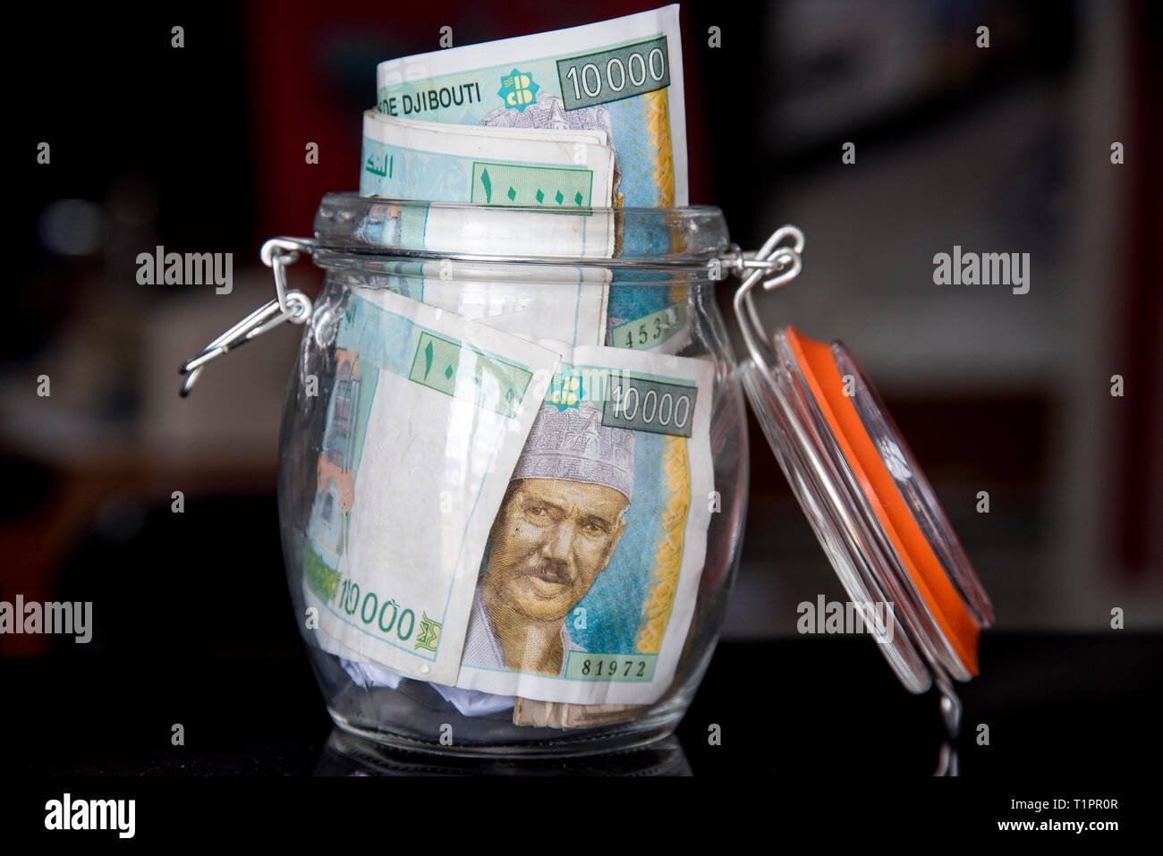 Ein Glas voll von 10.000 Dschibuti Franken - Einsparungen Stockfoto