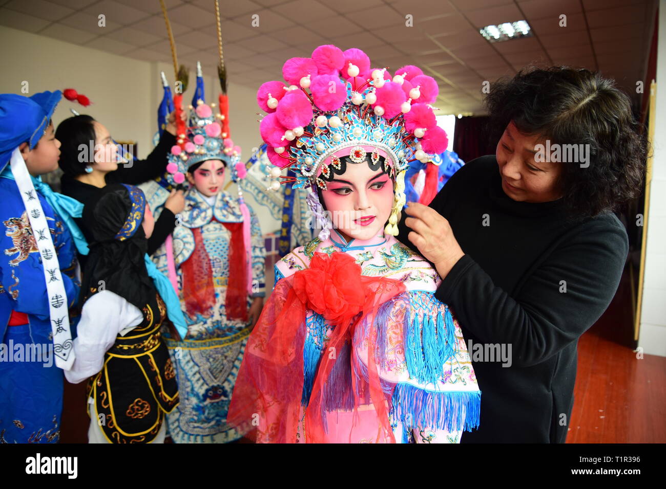 Peking, China. 27 Mär, 2019. Little Darsteller erhalten ihr Make-up mit Hilfe ihrer Lehrer an einer Grundschule in Jiashan, der ostchinesischen Provinz Zhejiang, am 27. März 2019, die Welt Theater Tag. Credit: Ning Wenwu/Xinhua/Alamy leben Nachrichten Stockfoto