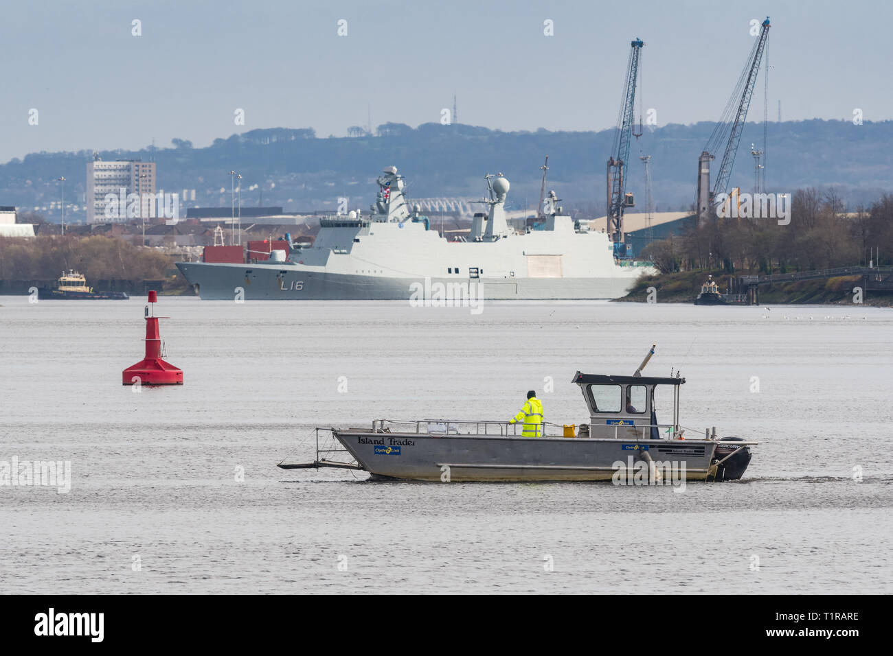 Glasgow, Schottland, Großbritannien. 28. März, 2019. Übung gemeinsame Krieger Vorbereitungen auf den Fluss Clyde in Glasgow. Die winzigen Renfrew Fähre - ein Passagier Fähren verbinden die nördlichen und südlichen Ufer des River Clyde in Glasgow - stellt eine Kreuzung nach dem riesigen Dänische HDMS Absalon L 16 vergeht vor Ihrer Teilnahme neben Kriegsschiffe, U-Boote und Flugzeuge aus 13 anderen Ländern für die zwei Wochen Übung in Schottland zwischen 30. März und 11. April Credit: Kay Roxby/Alamy leben Nachrichten Stockfoto