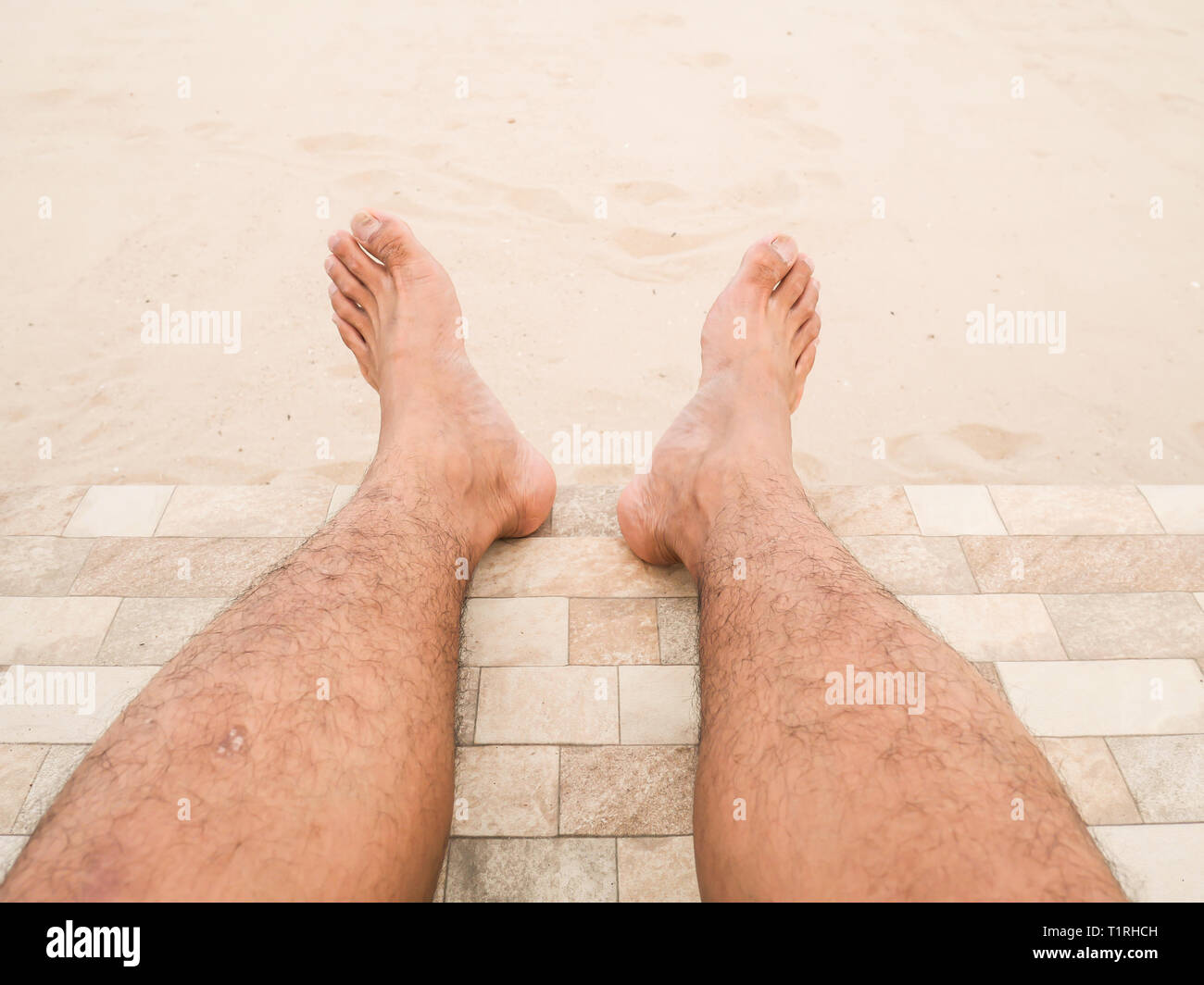 Mann ist entspannend barfuß am Strand. Nahaufnahme Beine haut Asien Mann und Männer behaarte Beine auf Sand Hintergrund. Guy's Beine in den Sand. Stockfoto