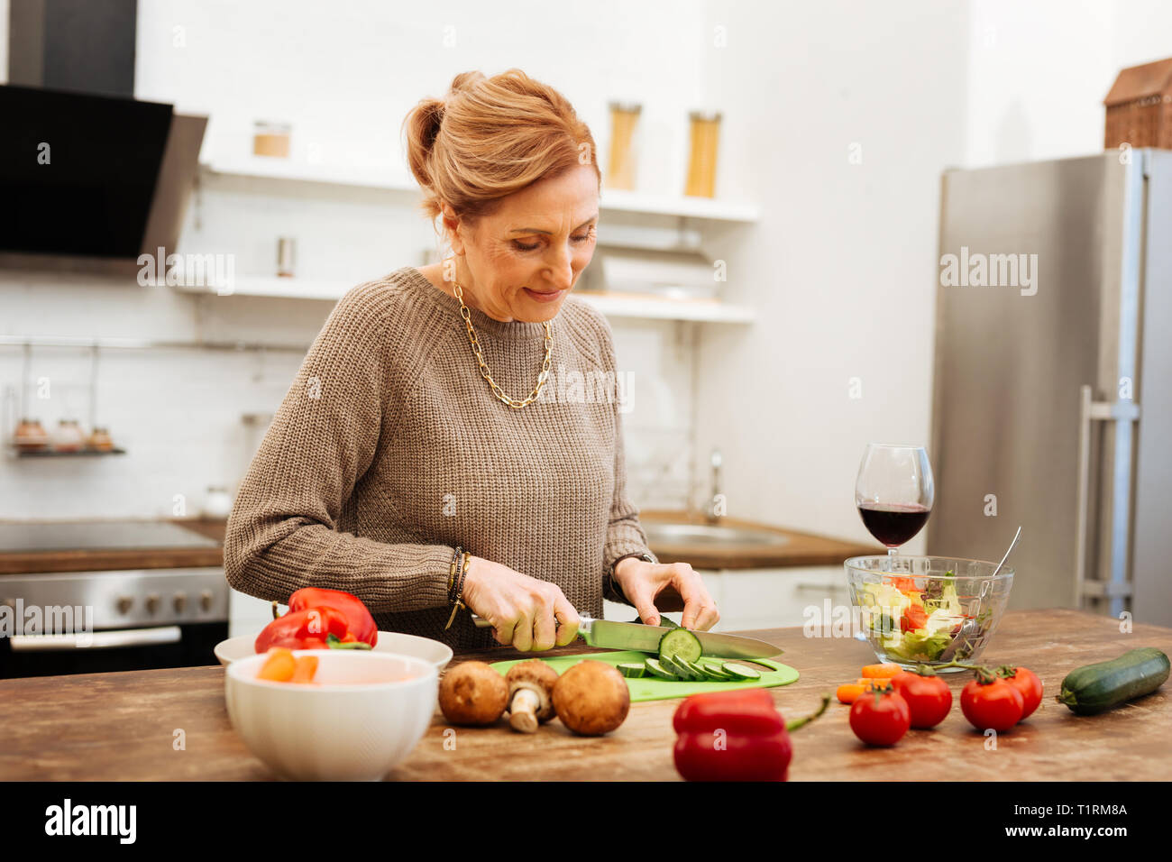 Reife Frau, Abendessen bereit, auf hölzernen Tisch konzentriert Stockfoto