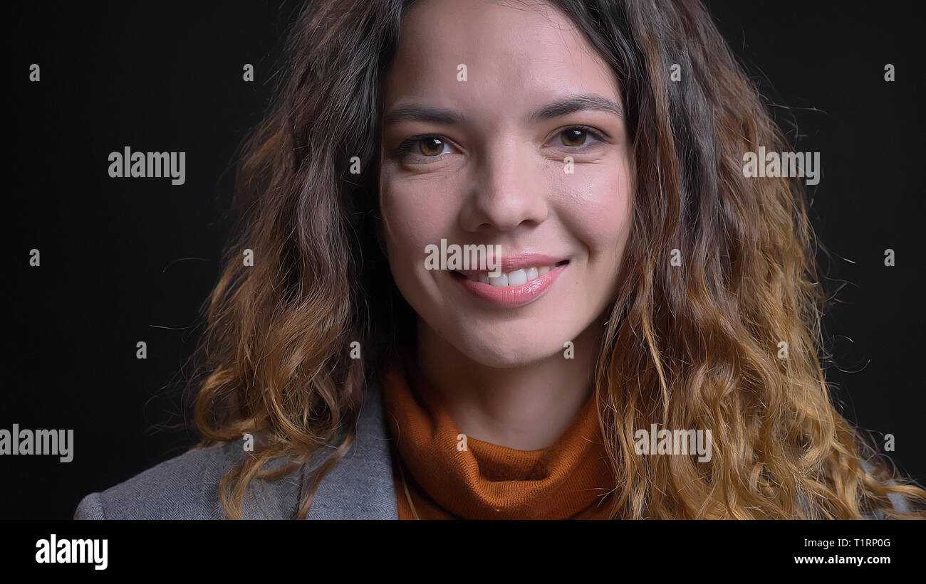 Closeup Shooting für junge attraktive kaukasische Geschäftsfrau, die gerade an der Kamera und glücklich lächelnd mit Hintergrund auf Schwarz Stockfoto