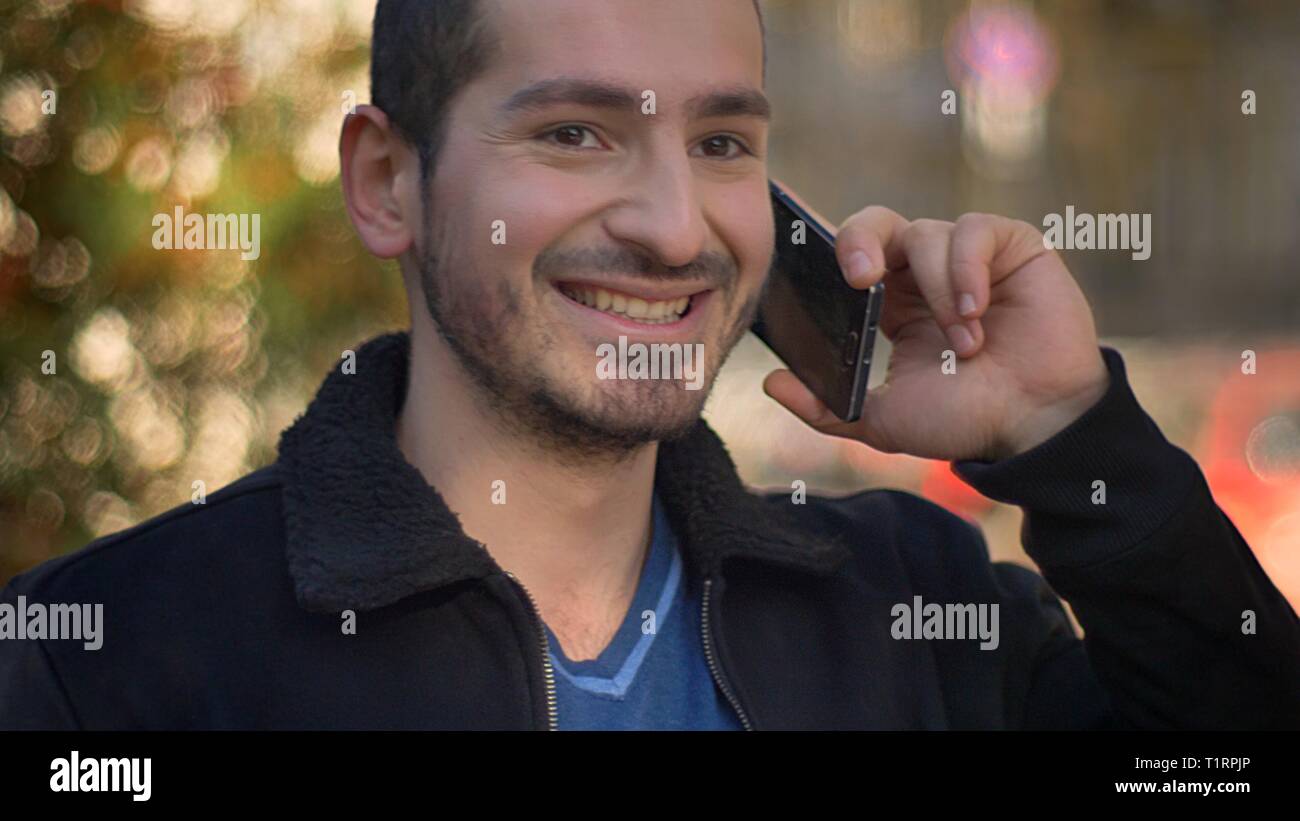 Portrait der kaukasischen Mann freudig Sprechen auf Smartphone und auf der Suche nach Links auf der Straße Hintergrund. Stockfoto