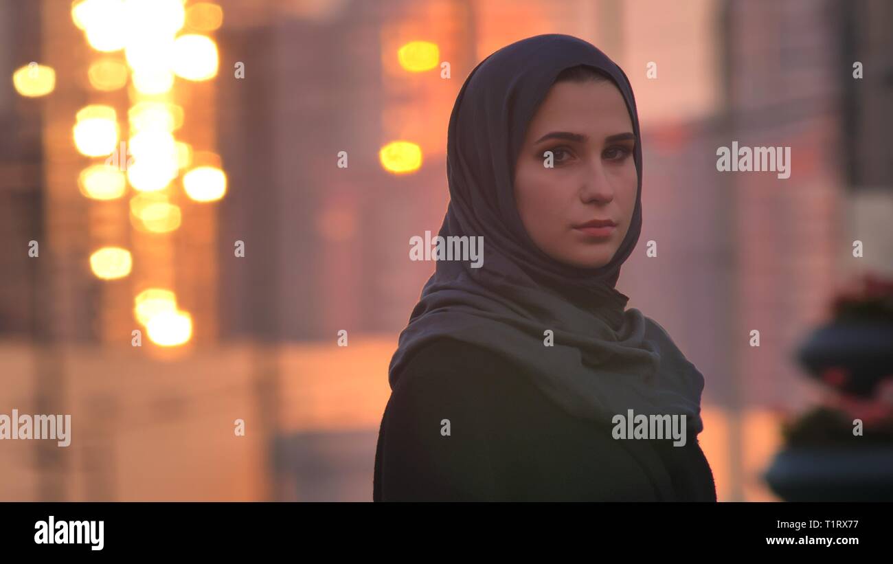 Closeup Portrait von jungen hübschen Frau im hijab drehen und Kamera mit Stadt und glänzende Gebäude auf dem Hintergrund Stockfoto