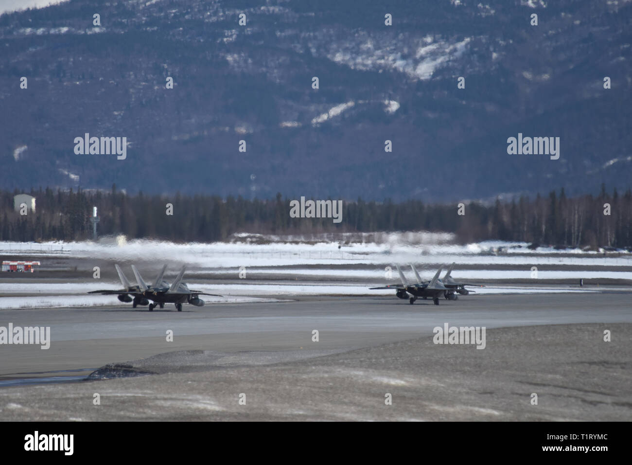 F-22 Raptors aus der 3 Flügel und 477th Fighter Group beteiligen sich in einer engen Formation Taxi, bekannt als ein Elephant Walk, 26. März 2019, während eines Polar Kraft Übung in Joint Base Elmendorf-Richardson, Alaska. Dieser zweiwöchige Übung gibt staffeln die Möglichkeit, ihre Fähigkeiten unter Beweis zu stellen, Bereitstellung und überwältigende Combat Power liefern. (U.S. Air Force Foto von Sheila deVera) Stockfoto