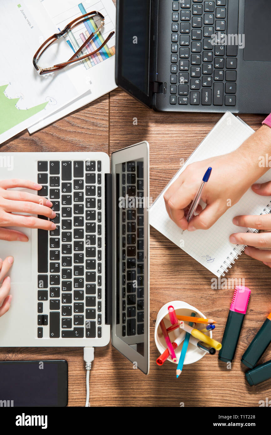 Zwei Personen im Büro Schreibtisch arbeiten, schreiben und mit Laptop, Ansicht von oben, flach. Smart Watch an Hand und Smart Phone auf dem Tisch. Kaffeetasse Stockfoto