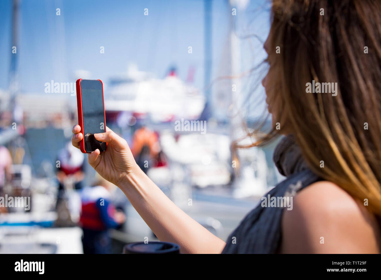 Schöne Frau mit Foto mit Smart Phone. Bild von Hafen mit Segelbooten, am Meer. Sonnigen Sommer bucht. Die selfie und Kaffee zu trinken. Stockfoto