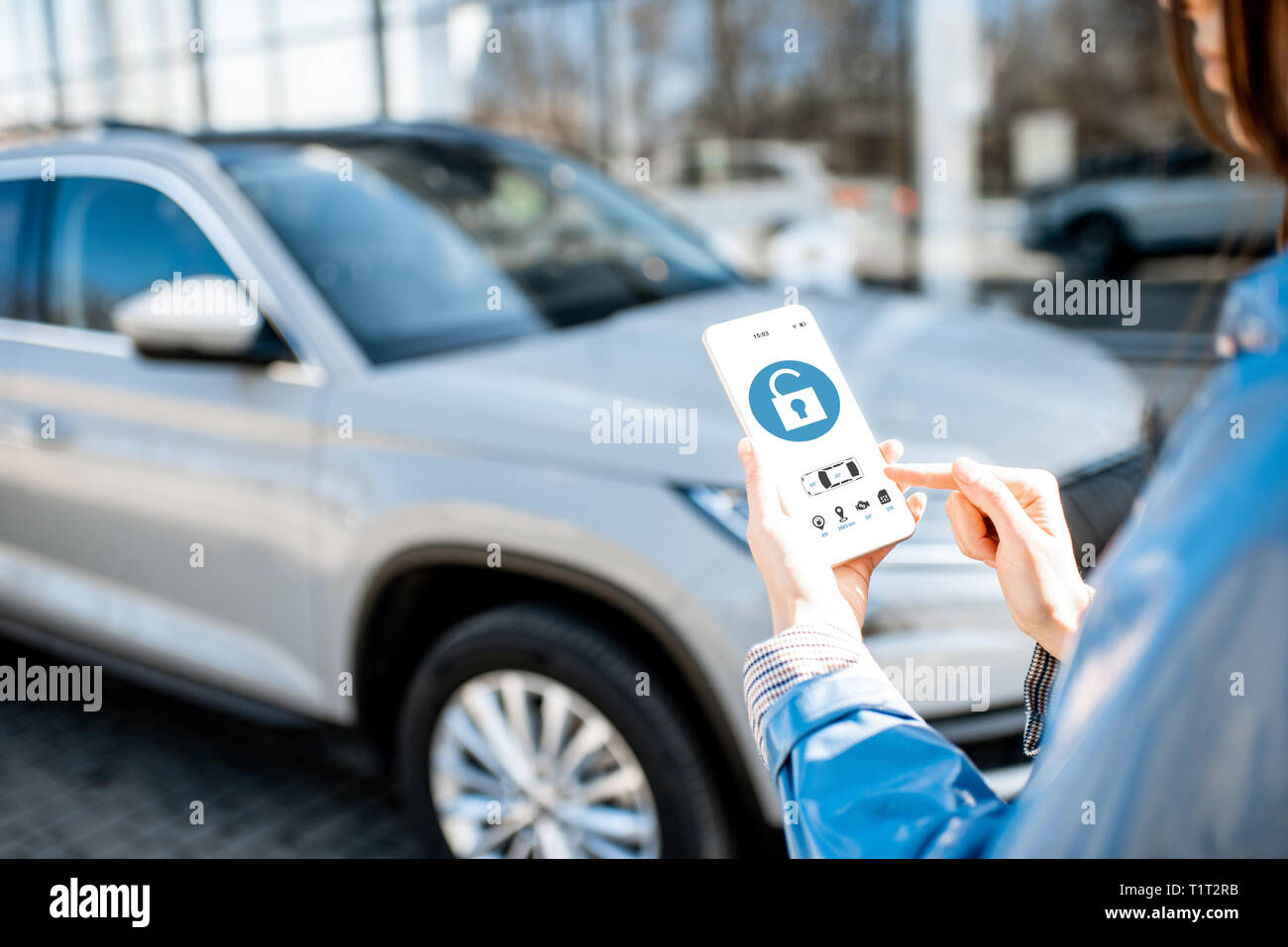 Frau Entriegelung mittels mobile Anwendung auf einem Smartphone. Konzept der Fernbedienung und Auto Schutz durch das Internet Stockfoto