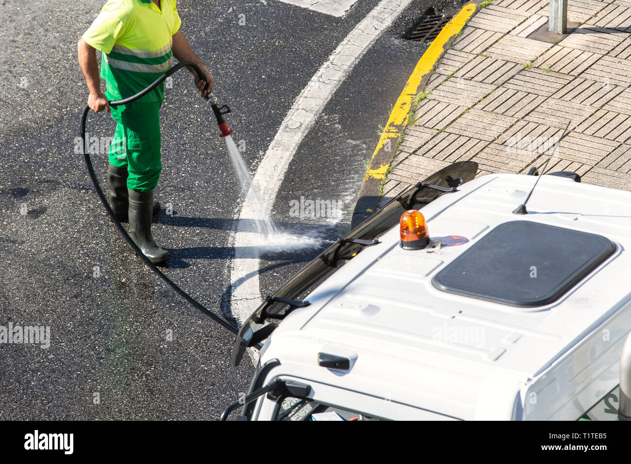 Arbeitnehmer Reinigung der Straße und Straße Gehweg mit hohem Druck Wasser. Öffentliche Wartungskonzept Stockfoto